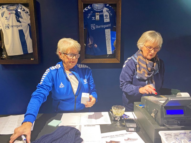 Aase Aastorp og Ellen Bjørnsen fra Damegruppa bak disken i Julebutikken til Sarpsborg 08, som i år er i Storbyen.